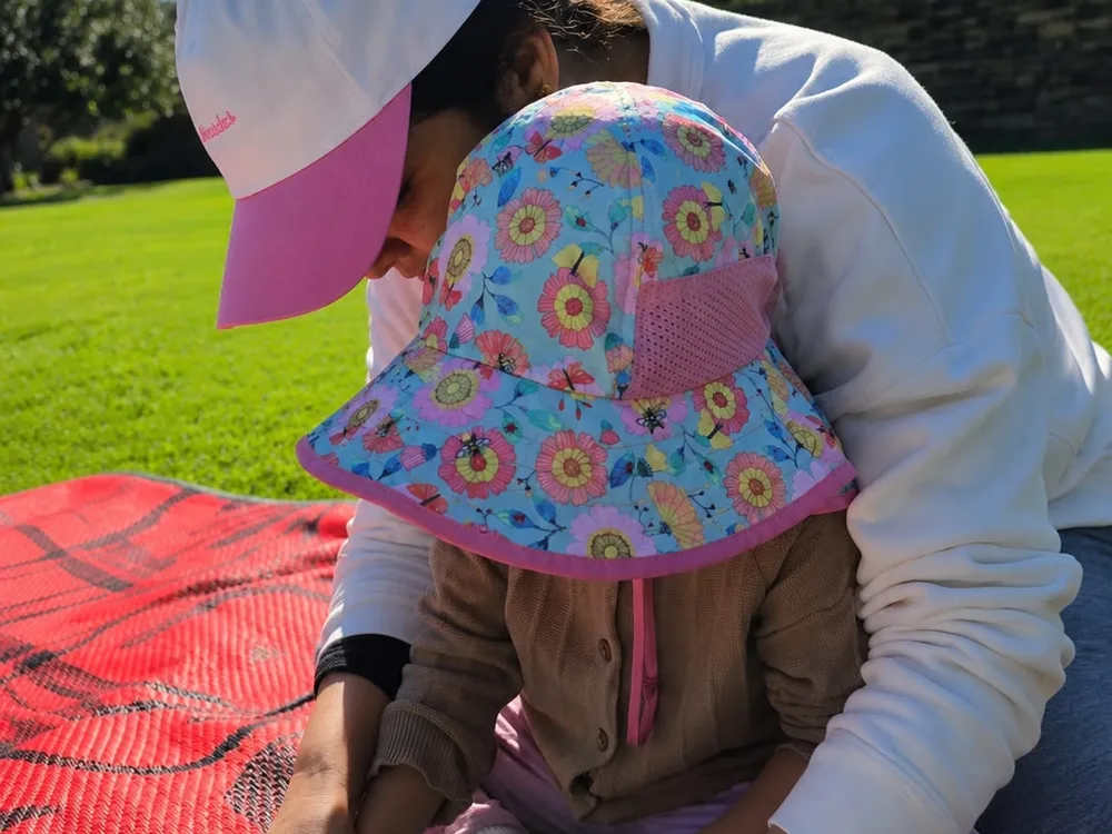 A Kuddles educator helping a child with a craft activity outdoors